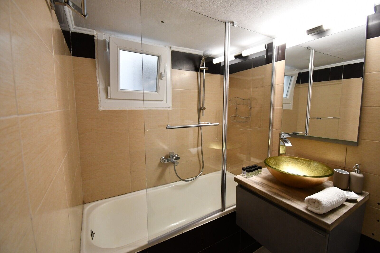 A modern bathroom with a glass-enclosed shower, a large mirror, and a wooden vanity with a glass bowl sink.