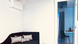 A modern room with a black sofa, a small table, and a chair. There is a door leading to another room. - Gentile Suite Decumani (Naples)