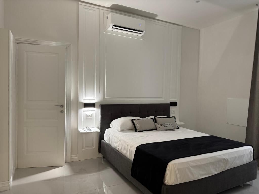 Une chambre à coucher comprenant un lit, une table de chevet, un climatiseur fixé au mur et une porte.
