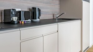 A modern kitchen with a wood-textured backsplash, a built-in microwave, and a stainless steel sink. - D52/3 one bedroom apartment (Budapest)