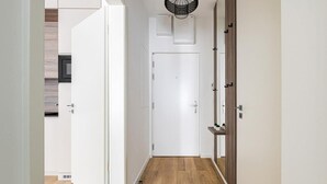 A hallway with a white door, wooden flooring, and a ceiling light fixture. - D52/3 one bedroom apartment (Budapest)