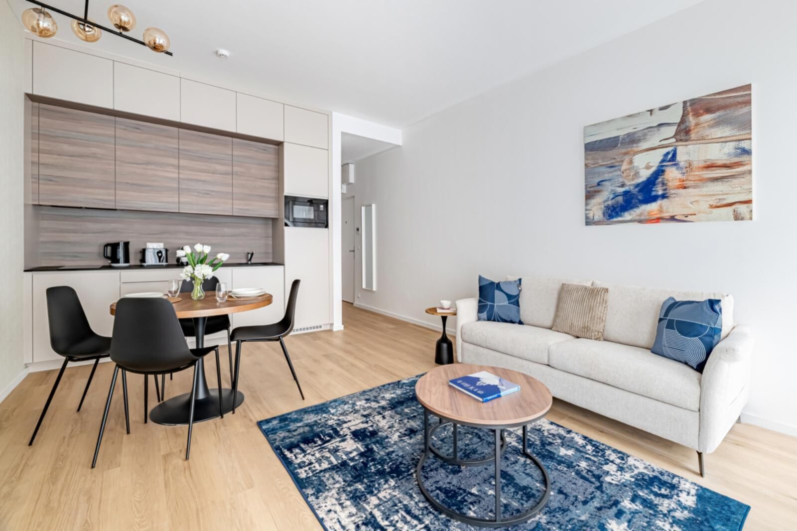 A modern living room with a sofa, coffee table, and a dining area with chairs and a table.