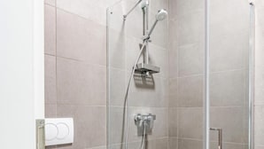 Un baño moderno con ducha de vidrio, inodoro y lavamanos.