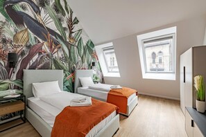 Ein modernes Hotelzimmer mit zwei Betten, einem großen tropischen Wandbild und großen Fenstern mit Blick auf die Stadt.