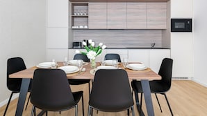 Un comedor moderno con una mesa de madera, sillas negras y un jarrón de flores blancas.