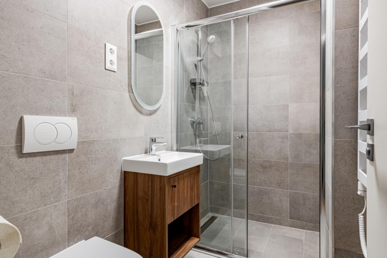 Une salle de bain moderne avec une douche à parois de verre, un meuble-lavabo en bois et un miroir fixé au mur.
