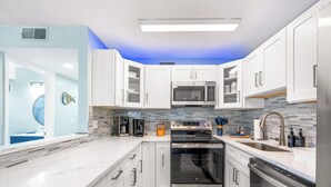 Una cocina moderna con armarios blancos, electrodomésticos de acero inoxidable y un salpicadero de azulejos azules.