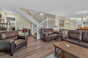 A spacious living room with a staircase, leather sofas, and a wooden coffee table. - Steps to the Beach and Prom; Beautiful Open 3-Bedroom Home (Seaside)