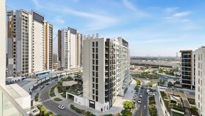 A high-rise residential building with multiple floors, a curved road, and surrounding greenery. - Bright Modern Studio in Meydan (Dubai)