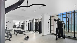 A modern gym with various exercise equipment, large windows, and a clean, spacious layout. - Bright Modern Studio in Meydan (Dubai)