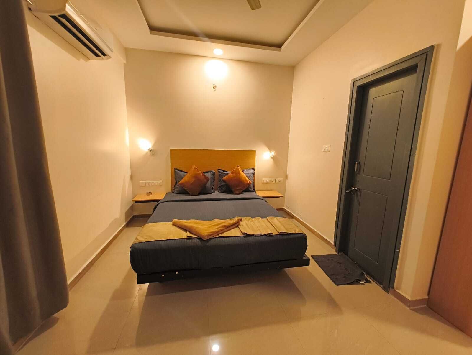 A hotel room with a bed, bedside tables, a wardrobe, and a ceiling fan.