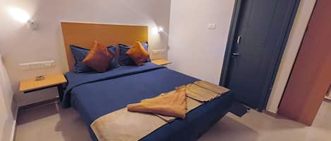 Ein Schlafzimmer mit einem Bett, einem Nachttisch, einer Tür und einer Wandleuchte.