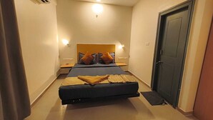 A hotel room with a bed, bedside tables, a wardrobe, and a ceiling fan. - Apex Inn Manyata (Bengaluru)