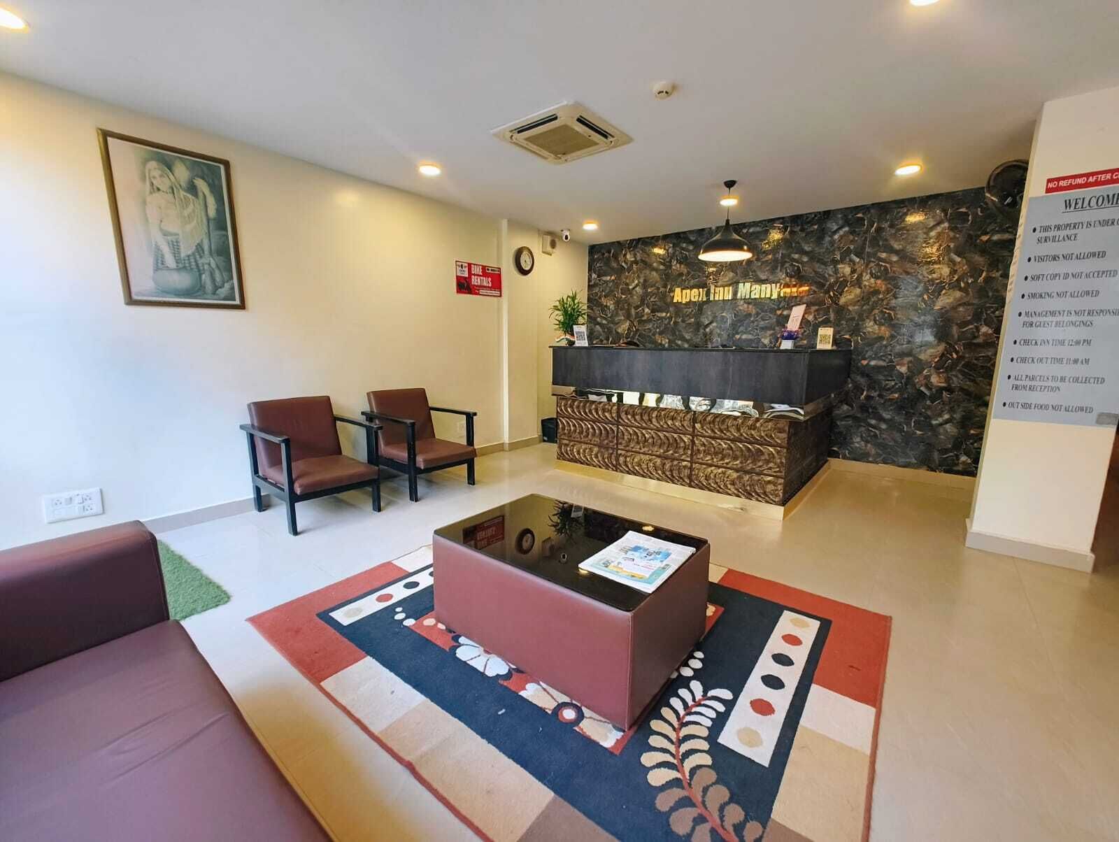 A reception area with a reception desk, two brown chairs, a red sofa, and a patterned rug.