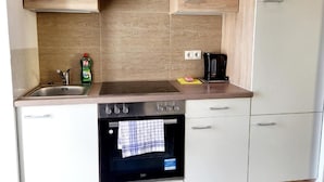 A modern kitchen with wooden cabinets, a stainless steel sink, a coffee maker, and an oven. - City Home Lifestyle Vienna (Vienna)