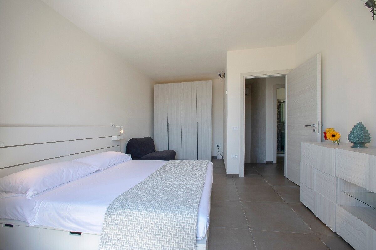 Una camera da letto con un letto, una sedia, un armadio e una porta che dà su un'altra stanza.