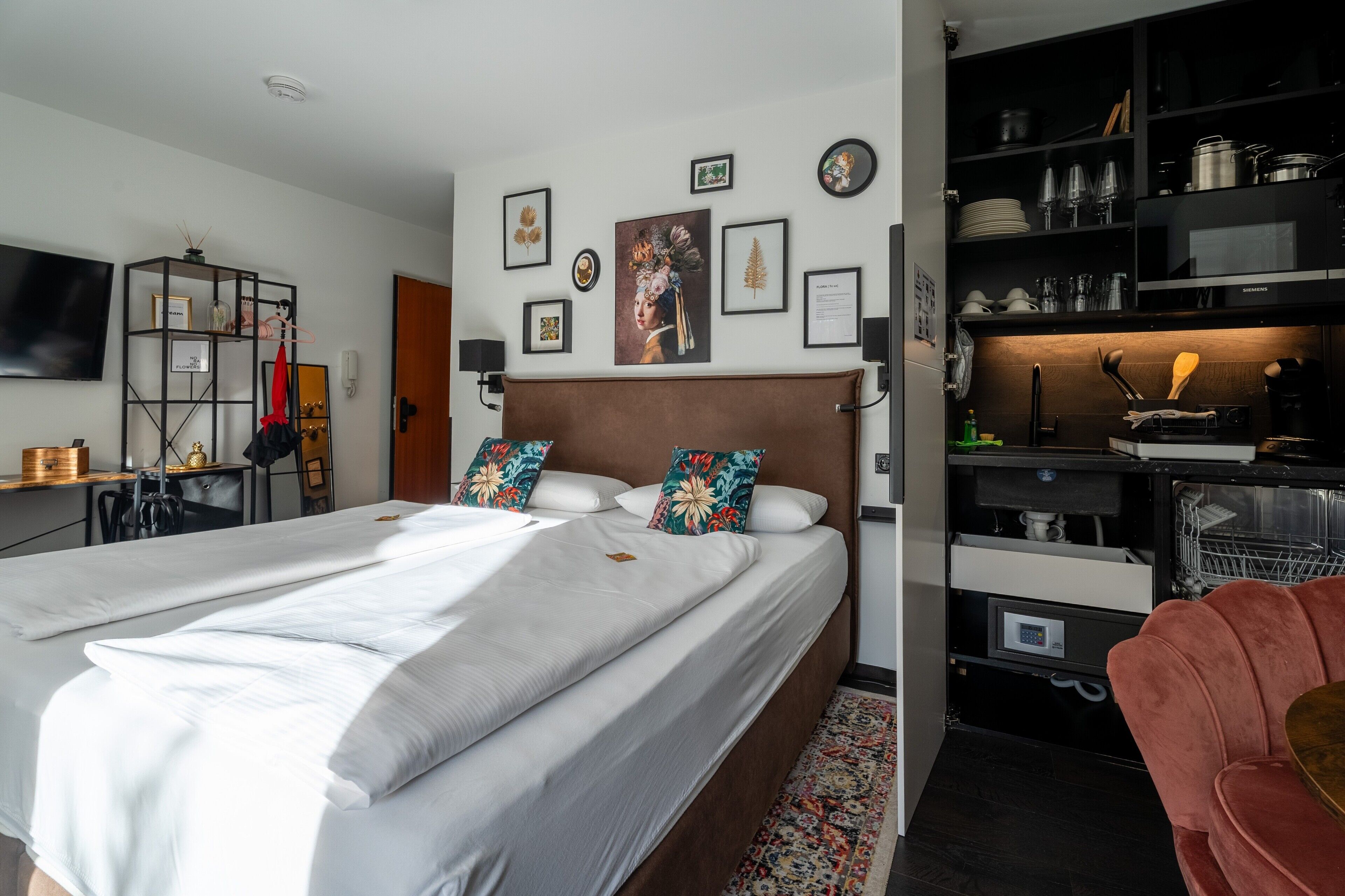 A neatly arranged hotel room with a large bed, a desk, a wardrobe, and a television.
