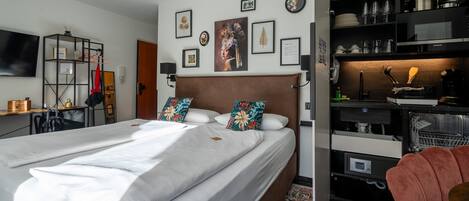 A neatly arranged hotel room with a large bed, a desk, a wardrobe, and a television.