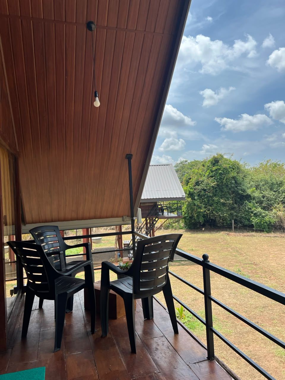 An outdoor seating area with a wooden ceiling and a view of a grassy field.