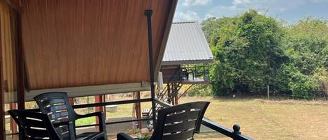 An outdoor seating area with a wooden ceiling and a view of a grassy field.