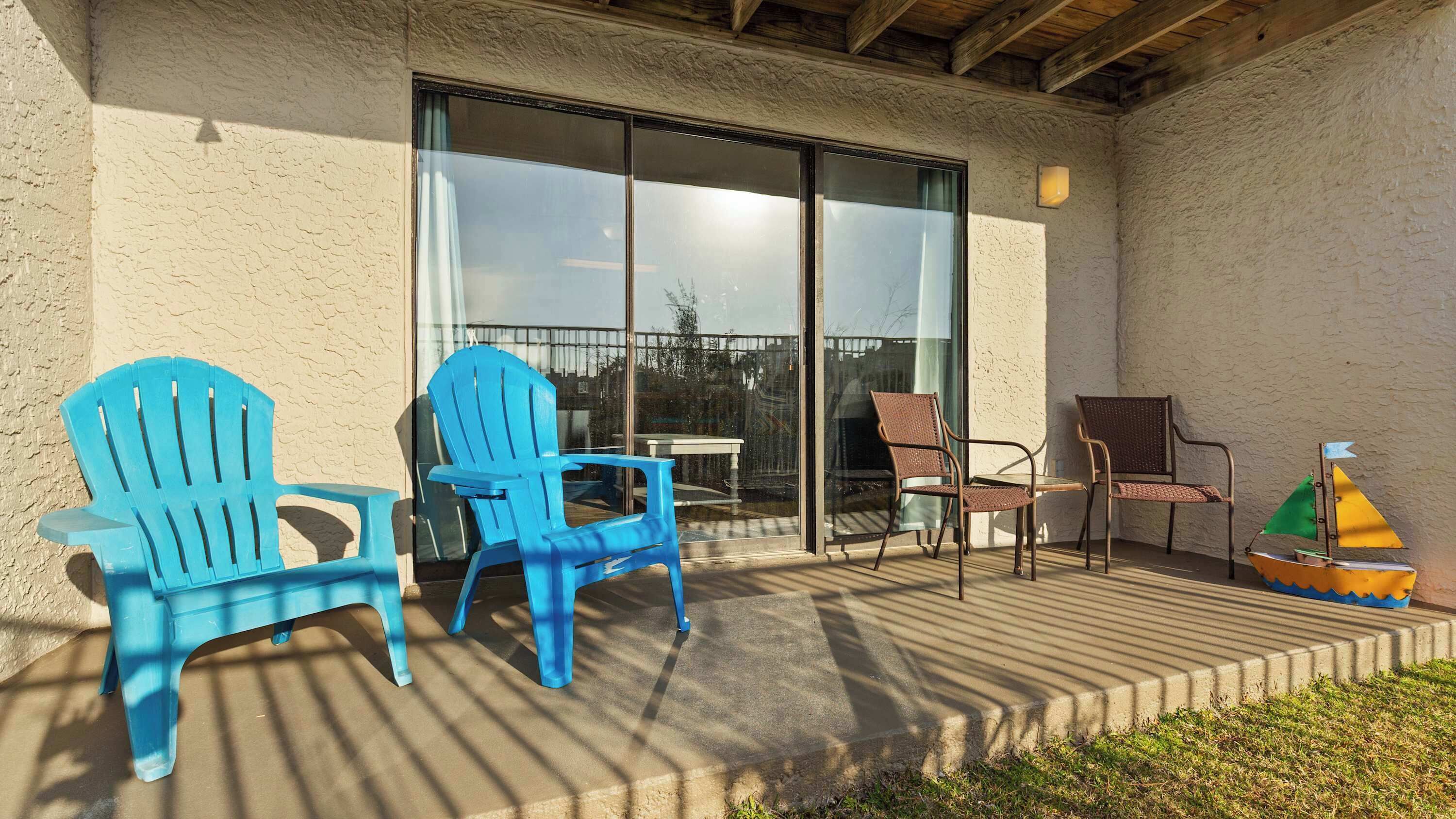 A patio with outdoor furniture, including chairs and a table, and a small boat decoration.