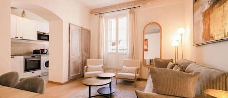 A modern living room with a sofa, armchairs, a coffee table, and a dining area with a table and chairs.