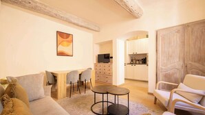 Un salon confortable avec un canapé, des fauteuils, une table basse et un coin cuisine équipé de placards et d’un téléviseur.