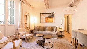 Un salon chaleureux avec un canapé, des fauteuils, une table basse et un tableau accroché au mur.