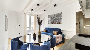 Un salon moderne avec une table ronde en verre, des canapés bleus et un vase décoratif.