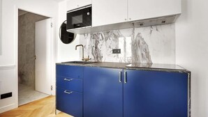 Une cuisine moderne avec un micro-ondes noir, des armoires bleues et un pare-feu en marbre.