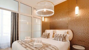 Een moderne slaapkamer met een groot bed, een gestructureerde wand en hanglampen.