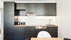 Una cocina moderna con armarios oscuros, una campana extractora de acero inoxidable, un salpicadero de azulejos blancos y una encimera de madera.