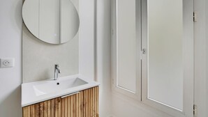 Un bagno moderno con uno specchio rotondo, un lavabo bianco e mobili in legno.