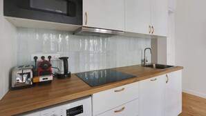 Una cucina moderna con mobili bianchi, un forno a microonde nero, una macchina per caffè e un tostapane.