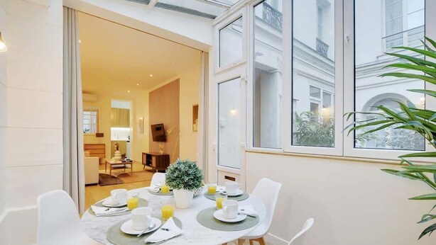 A dining area with a table set for breakfast, including plates, cups, and a potted plant. - An Amazing 2-BR in Le Marais (Paris)