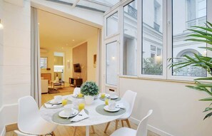 A dining area with a table set for breakfast, including plates, cups, and a potted plant. - An Amazing 2-BR in Le Marais (Paris)