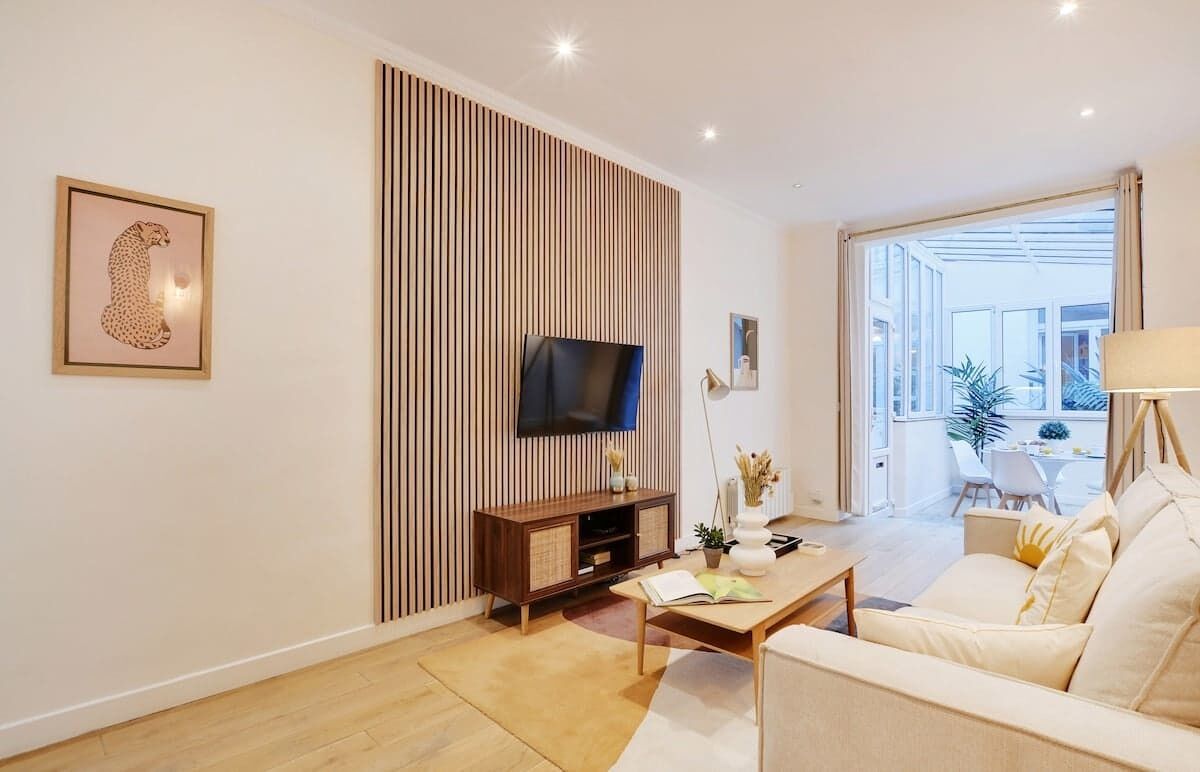 Una sala de estar moderna con una televisión de pantalla plana, un sofá, una mesa de centro y una estantería.