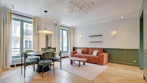 Una sala moderna con una mesa redonda, un sofá y una zona de comedor con sillas.