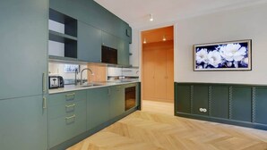 Una cocina moderna con gabinetes color turquesa, piso de madera en patrón de espiga y una obra de arte floral enmarcada en la pared.