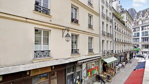 En gatubild från en europeisk stad med byggnader som har balkonger, butiksfasader och uteserveringar.