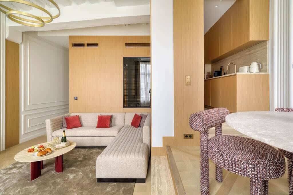 Una sala de estar moderna con un sofá, un reposapiés y una mesa de comedor con sillas.