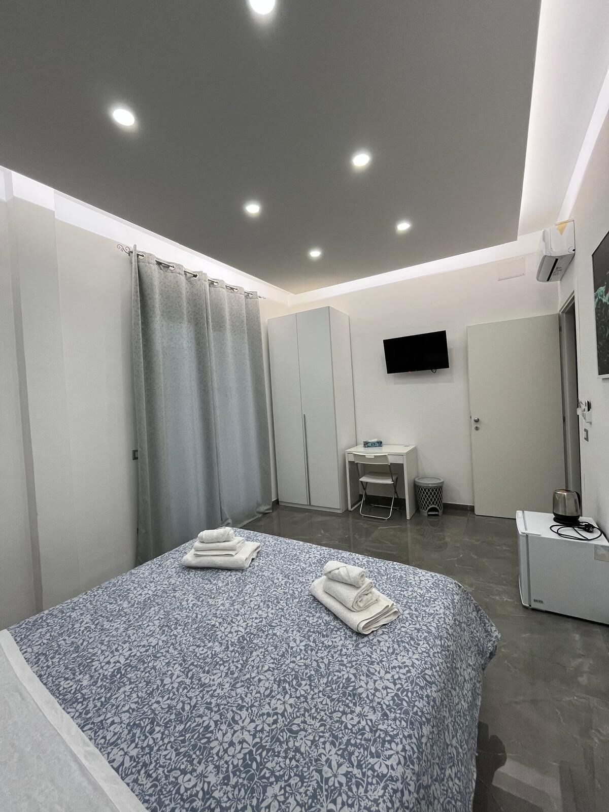 Une chambre d’hôtel moderne équipée d’un grand lit, d’un bureau, d’une chaise, d’une télévision et d’une petite kitchenette.