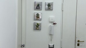 A hallway with a white door, a security camera, and three framed pictures of plants. - Napolitudine (Naples)