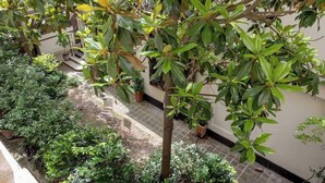 En innergård med ett stort utbud av krukväxter och en liten sittplats.