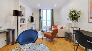 Una sala de estar moderna con un sofá, sillas, una mesa de centro y un televisor.