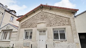 A building with a stone facade, a white door, and barred windows.