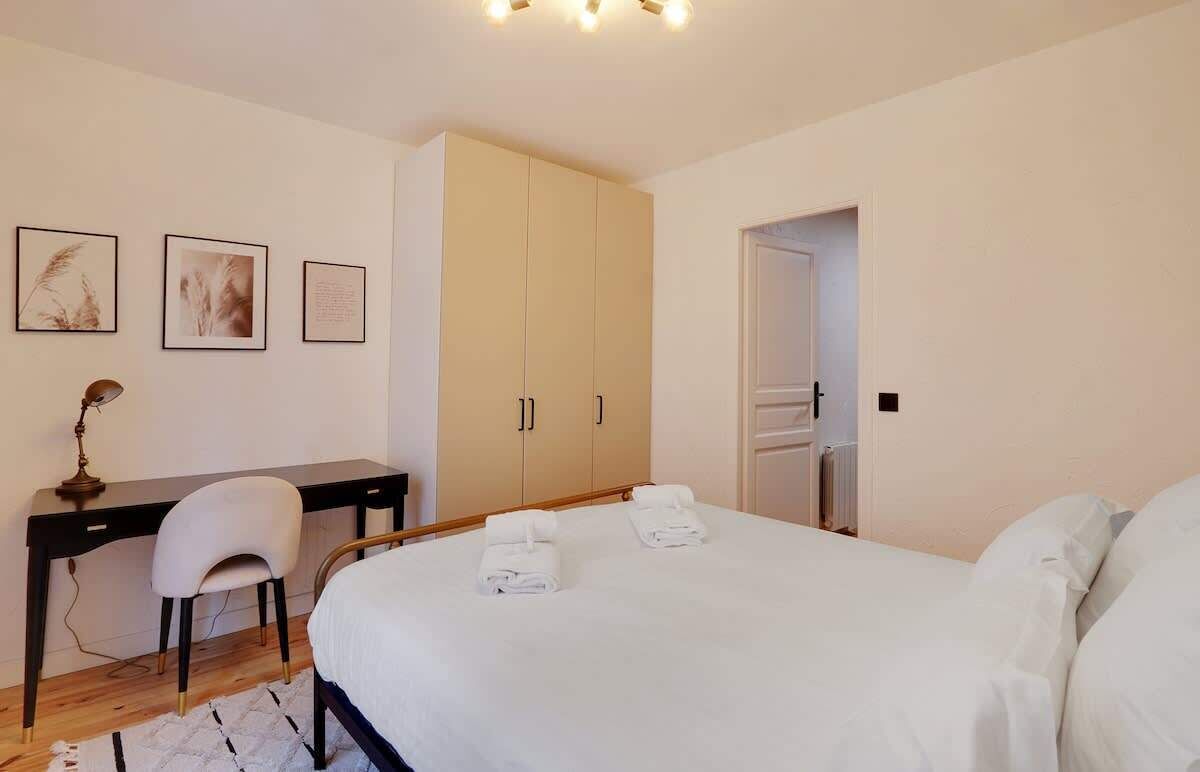 Une chambre à coucher avec un lit, un bureau, une chaise et une armoire.