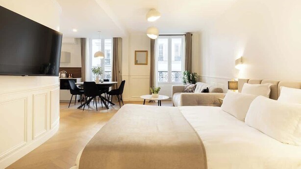 Ein modernes Hotelzimmer mit einem großen Bett, einem Essbereich und einem Fernseher.