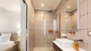 Ein modernes Badezimmer mit Dusche, einem großen Spiegel und einem Waschtisch mit Waschbecken.