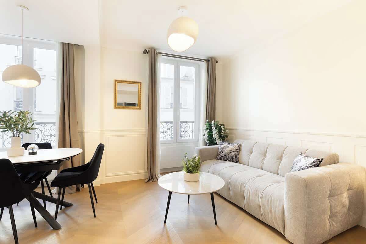 Una sala moderna con un sofá, una mesa redonda de centro y una mesa de comedor con sillas.